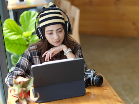 Portrait of female photographer working with digital tablet and headphone on wooden table