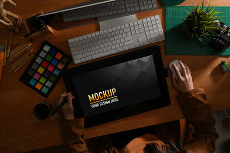 Overhead shot of female graphic designer working with designer tools and mock up drawing tablet