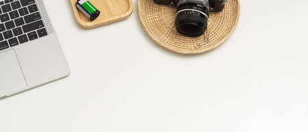 Cropped shot of white table with laptop, camera and copy space in home office room