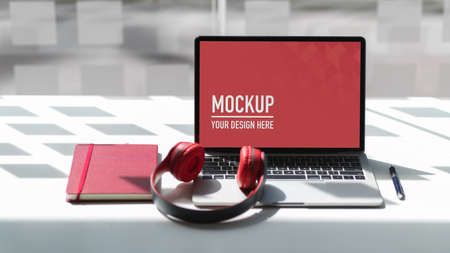 Close up view of worktable with mock up laptop, headphone and notebook in glass wall co working...