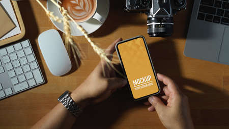 Top view of male using mock up smartphone on wooden computer desk, clipping path