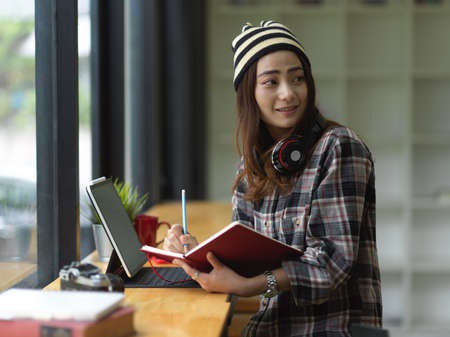 Female working on her assignment while writing on notebook in comfortable workspace