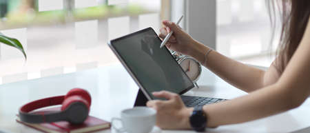 Side view of female hands using digital tablet on white table in co working space