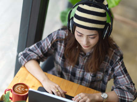 Overhead shot of female teenager with headphone working with tablet in cafeの写真素材