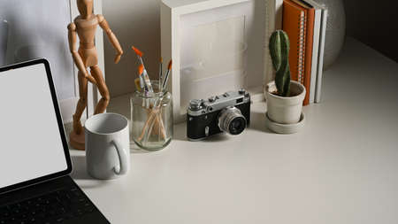 Cropped shot of worktable with digital tablet, camera, paint brushes, decorations and copy space