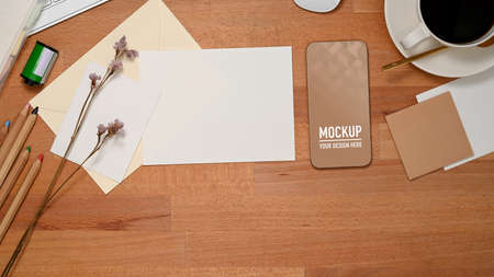 Top view of workspace with smartphone, mock up paper card, coffee cup and stationeryの写真素材