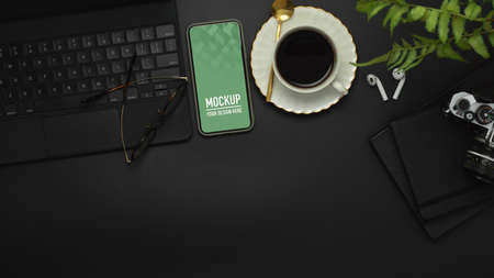 Top view of workspace with smartphone, keyboard, camera, coffee cup and supplies