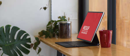 Side view of portable workspace with tablet and coffee mug on wooden bar in cafe