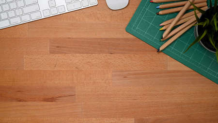 Top view of wooden table with copy space, coloured pencils, computer device in home office roomの写真素材
