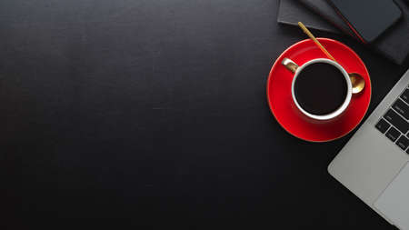 Top view of black table with copy space, coffee cup, laptop and notebooksの写真素材