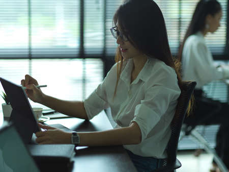 Side view of female office worker working with tablet in office room