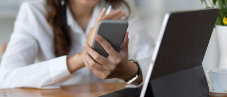 Close up view of female using smartphone while sitting at workplace
