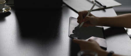 Side view of female hands using digital tablet with stylus pen on meeting table
