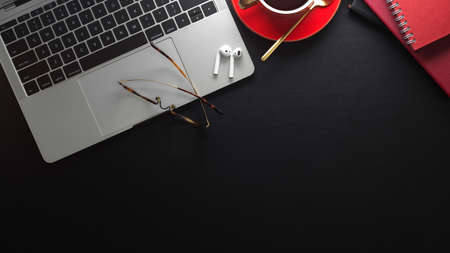 Top view of modern workspace with laptop, coffee cup and office supplies on black tablet with copy...