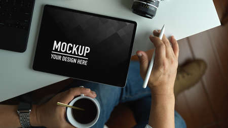 Top view of man working on blank screen tablet while drinking coffee cup in workspace, include clipping pathの写真素材