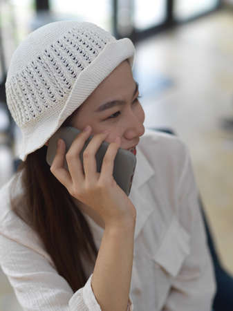 Portrait of female teenager smiling and talking on the phone while sitting in cafe