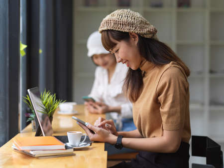 Cropped shot of young female using smartphone in comfortable workspaceの写真素材