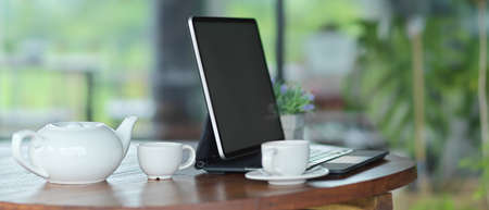 Side view of comfortable workspace with mock up blank screen tablet with keyboard with pottery...