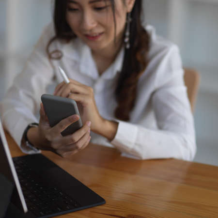 Close up view of female take a break and using smartphone while working in office room