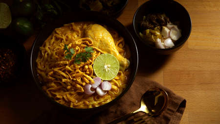 Top view of Northern Thai food, Noodles curry soup with Chicken (Khao Soi) serving on wooden tableの写真素材