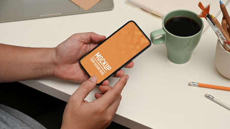 Cropped shot of male hands using smartphone on workspace