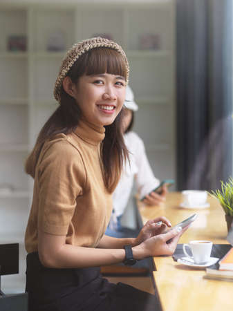 Portrait of female teenager looking into camera while doing assignment in cafeの写真素材
