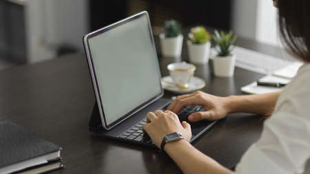 Cropped shot of young female office worker typing on laptop computer in modern office room
