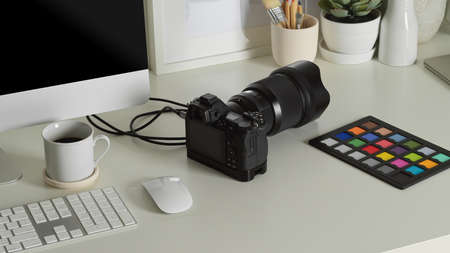 Close up view of worktable with camera, colour checker, computer device and decorationsの写真素材