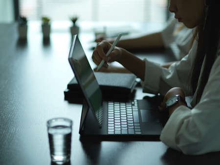 Side view of office workers working with digital tablet on meeting table