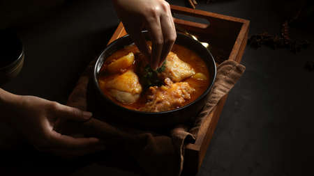 Cropped shot of female hand cooking chicken Massaman Curry to serve in Thai restaurant