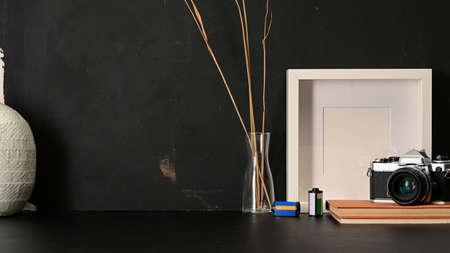 Close up view of worktable with mock up frame, camera, stationery, decorations and copy space