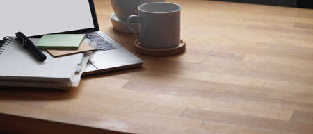 Cropped shot of wooden table with stationery, laptop, coffee mug and copy space