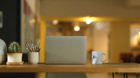 Close up view of workspace with laptop, mug and decorations on wooden table in home officeの写真素材