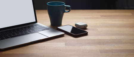 Cropped shot of wooden table with laptop, smartphone, mug and copy space, clipping pathの写真素材