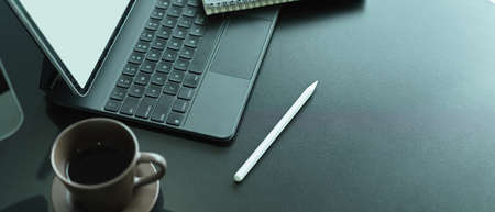 Side view of office desk with mock up laptop, keyboard, stylus, coffee cup and copy spaceの写真素材