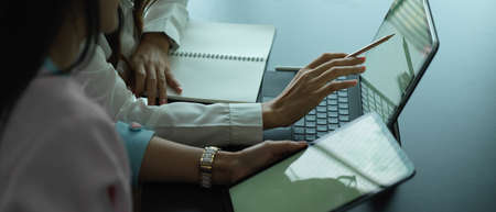 Side view of two female workers working together on their project with digital devicesの写真素材