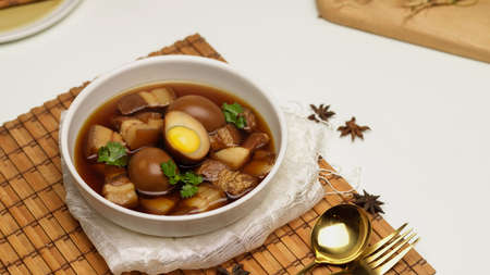 Close up view of sweet brown stewed eggs soup (Kai Palo) with pork on bamboo placemat on dinning tableの写真素材