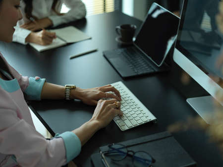 Cropped shot of  two female workers working together on their project with digital devices in...