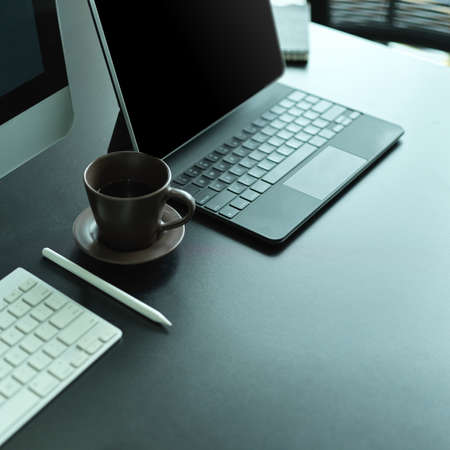 Side view of office desk with computer keyboard, laptop keyboard, coffee cup and copy space