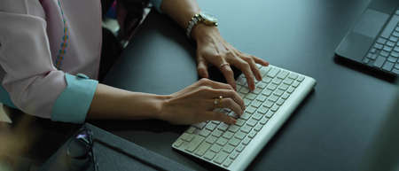 Cropped shot of female hands typing on computer keyboard on office deskの写真素材