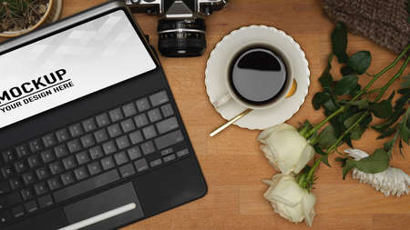 Top view of workspace with laptop, coffee cup, camera and flower decorated on the tableの写真素材
