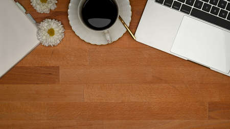 Top view of wooden table with laptop, coffee cup, copy space and flower decorated on the tableの写真素材