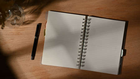 Top view of opened blank notebook and pen on wooden tableの写真素材