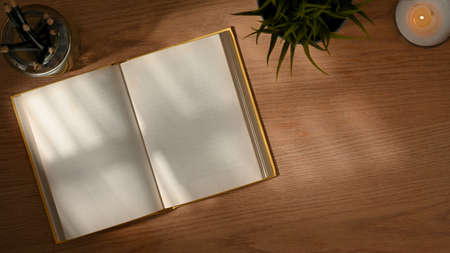 Top view of wooden table with opened blank notebook, decorations and copy spaceの写真素材