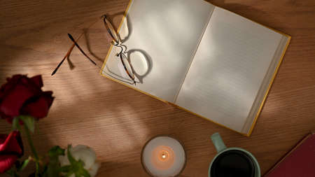 Top view of workspace  opened notebook, glasses and decorations on wooden tableの写真素材