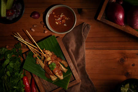 Top view of Grilled pork satay (Moo Satay) served with peanut sauce on the table with ingredientsの写真素材