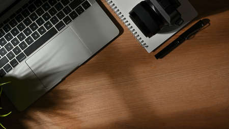 Top view of workspace with laptop, stationery, camera and copy space on wooden tableの写真素材