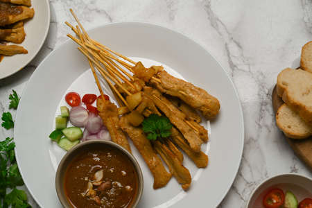 Top view of Grilled pork satay (Moo Satay) served with peanut sauce and grilled bread on marble deskの写真素材