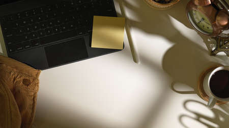 Top view of workspace with tablet, sticky note, coffee cup and copy space on white tableの写真素材