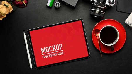 Top view of workspace with tablet, coffee cup, camera and supplies on black table, clipping path